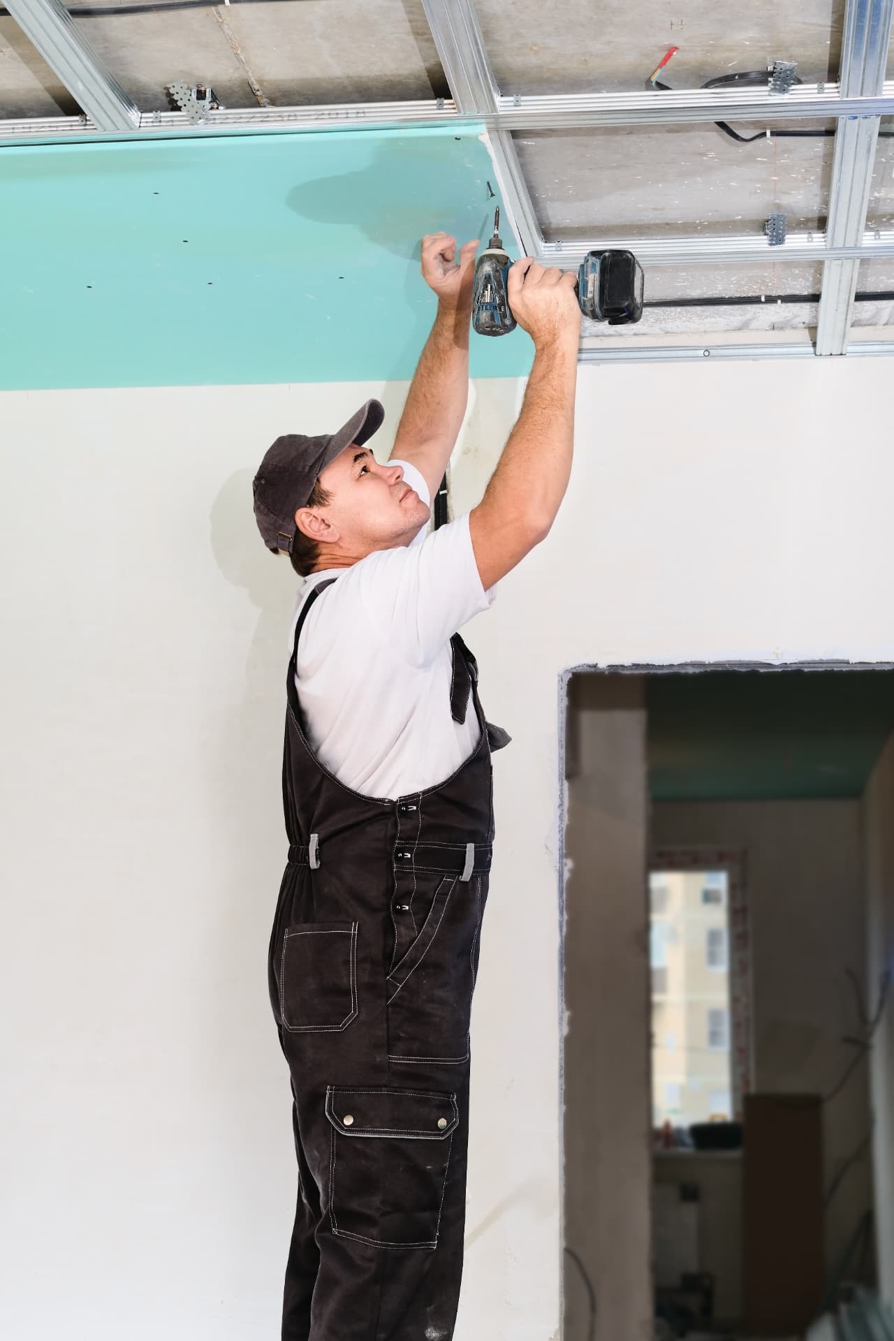 Profissional instalando placas de forro de drywall com parafusadeira